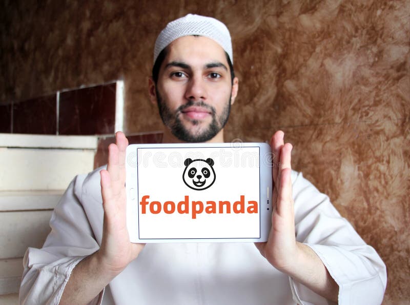 Logo of Foodpanda company on samsung tablet holded by arab muslim man. Foodpanda is a German mobile food delivery marketplace. The service allows users to select from local restaurants and place orders via its mobile applications as well as its websites. Logo of Foodpanda company on samsung tablet holded by arab muslim man. Foodpanda is a German mobile food delivery marketplace. The service allows users to select from local restaurants and place orders via its mobile applications as well as its websites