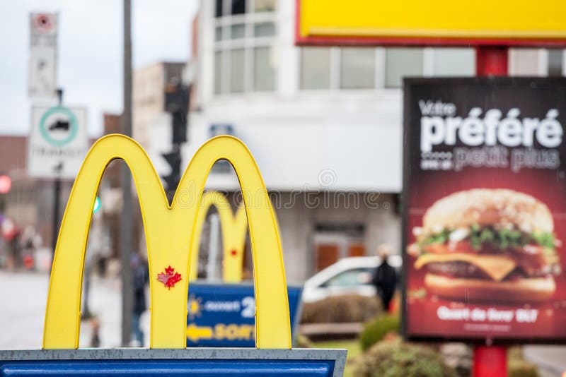 Logo Mc Donald's s Kanada mit seinem ikonenhaften M vor einem lokalen Restaurant, mit ikonenhaftem kanadischem Ahornblatt im M de stockbild Logo Mc Donald's s Kanada mit seinem ikonenhaften M vor einem lokalen Restaurant, mit ikonenhaftem kanadischem Ahornblatt im M de stockbild
