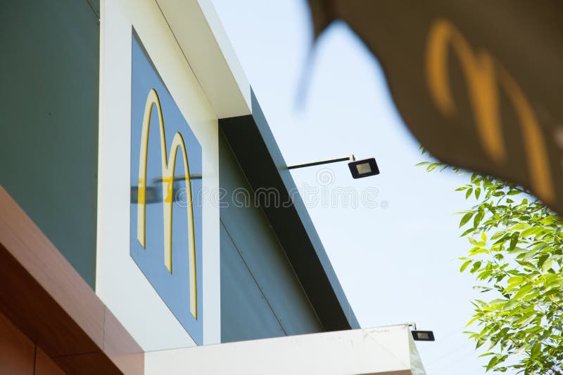 Logotipo del restaurante de los alimentos de preparaci?n r?pida de la letra M mcdonald en el tejado del edificio en una ciudad gr foto de archivo libre de regalías Logotipo del restaurante de los alimentos de preparaci?n r?pida de la letra M mcdonald en el tejado del edificio en una ciudad gr foto de archivo libre de regalías