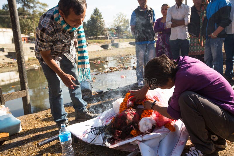 Lokalni ludzie podczas kremaci ceremonii wzdłuż świętej Bagmati rzeki w Bhasmeshvar Ghat przy Pashupatinath świątynią w Kathmandu zdjęcia stock Lokalni ludzie podczas kremaci ceremonii wzdłuż świętej Bagmati rzeki w Bhasmeshvar Ghat przy Pashupatinath świątynią w Kathmandu zdjęcia stock