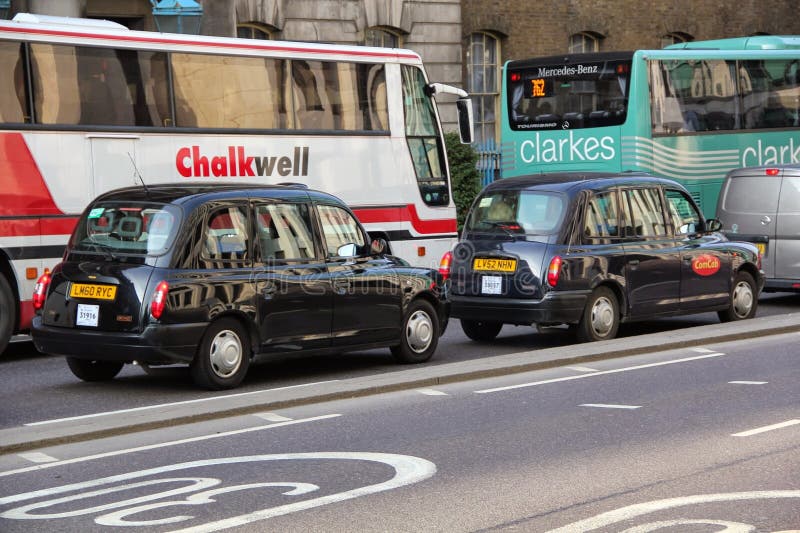 London black taxi following each other in front of the busses on the road