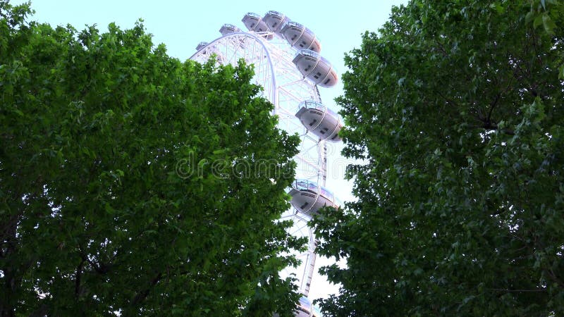 London Eye nel tramonto, la gente in parco di divertimenti, punto di vista di viaggio dei turisti