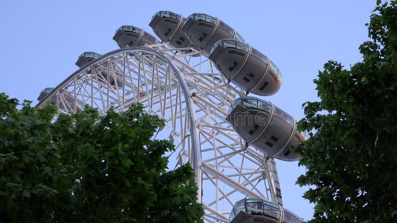 London Eye nel tramonto, la gente in parco di divertimenti, vista di viaggio del primo piano dei turisti