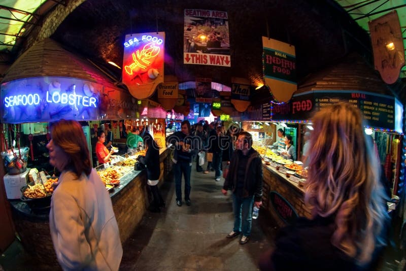 London, Förenade kungariket - den 1 april 2007: Okända köpare som går nära gatumatsalar i Camden Lock, känd marknad i Storbritann royaltyfri fotografi London, Förenade kungariket - den 1 april 2007: Okända köpare som går nära gatumatsalar i Camden Lock, känd marknad i Storbritann royaltyfri fotografi