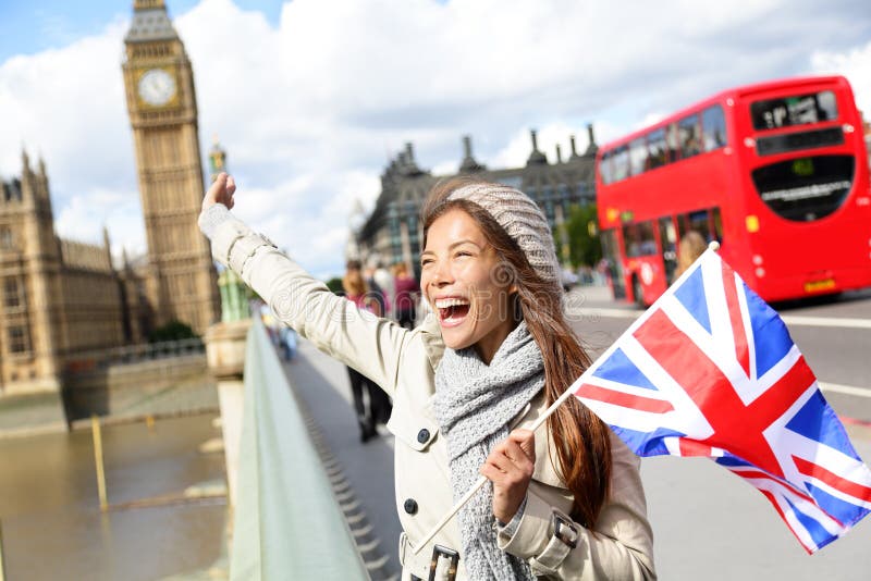 London - happy tourist holding British UK flag by Big Ben and red double decker bus. Excited girl sightseeing travel on Westminster Bridge, London, England, United Kingdom. Multiracial Asian Caucasian. London - happy tourist holding British UK flag by Big Ben and red double decker bus. Excited girl sightseeing travel on Westminster Bridge, London, England, United Kingdom. Multiracial Asian Caucasian