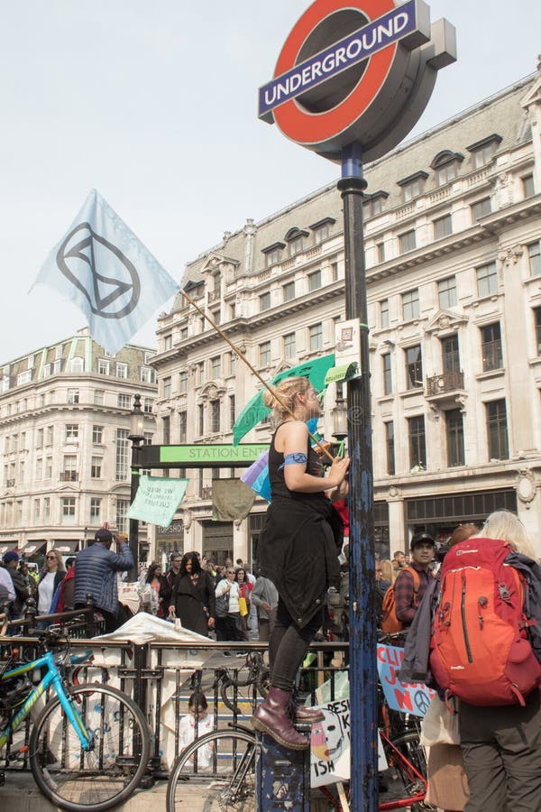 London, UK, April 17 2019 - Young female climate change protester waves an Extinction Rebellion flag outside Oxford Circus stock photo London, UK, April 17 2019 - Young female climate change protester waves an Extinction Rebellion flag outside Oxford Circus stock photo