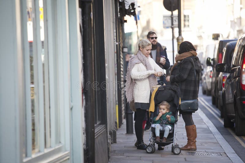 Two women with a stroller with a baby stand on the street Brick Lane royalty free stock image Two women with a stroller with a baby stand on the street Brick Lane royalty free stock image