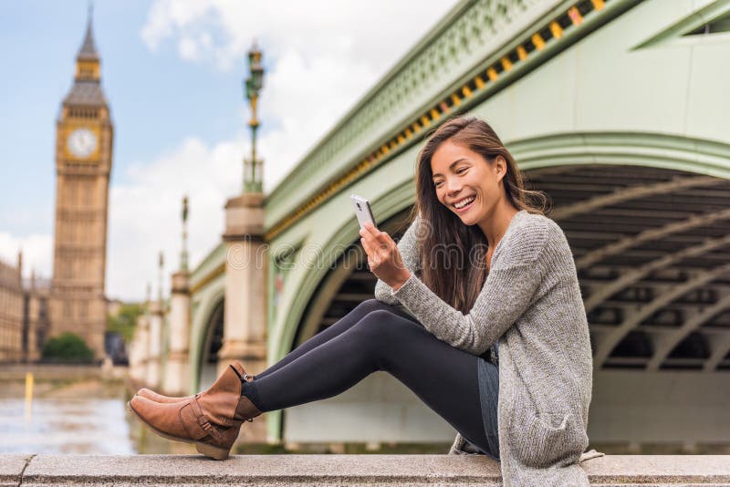 London urban people city lifestyle woman using phone app texting sms on social media. Young Asian girl holding cellphone