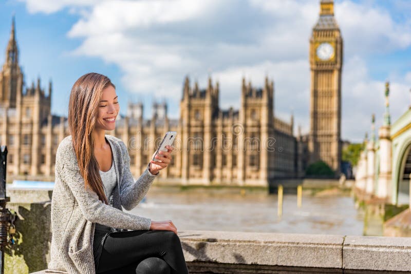 London urban people city lifestyle young Asian woman using mobile phone app texting sms on social media. Happy