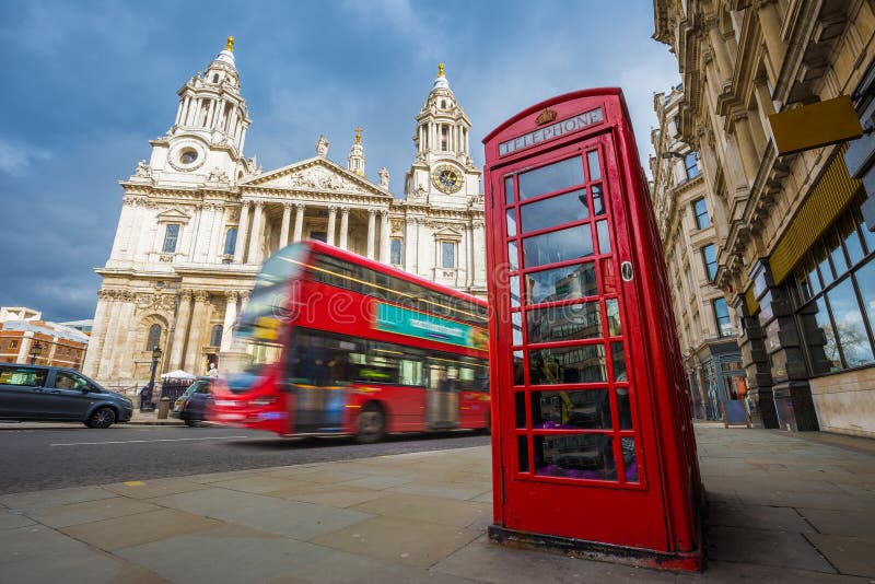 Londra, Inghilterra - cabina telefonica rossa tradizionale con l'autobus a due piani rosso iconico sul movimento alla cattedrale immagini stock Londra, Inghilterra - cabina telefonica rossa tradizionale con l'autobus a due piani rosso iconico sul movimento alla cattedrale immagini stock