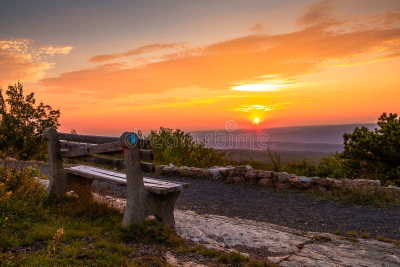 A lone bench looks over the mountain at sunset next to rock wall royalty free stock images A lone bench looks over the mountain at sunset next to rock wall royalty free stock images
