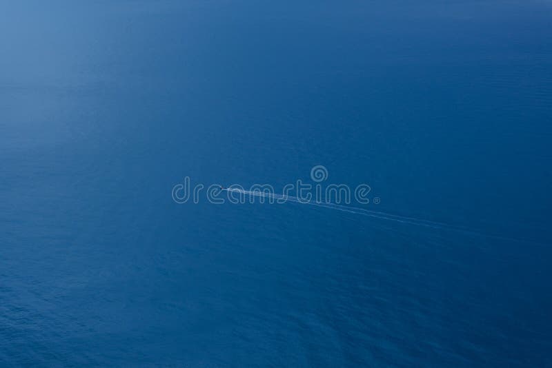 A lone boat in the endless blue sea. Top view of the sea background with the ship