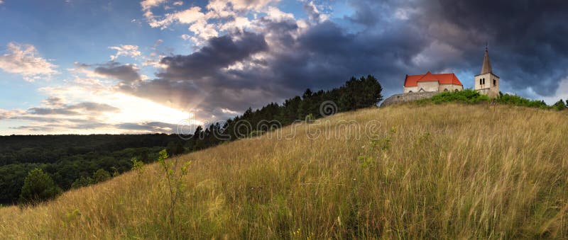 Lone Catholic church with dramatic clouds and sun