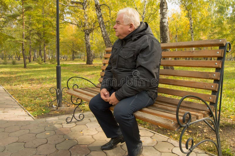 The lone gray-haired old man, resting on a wooden bench in a Park on a Sunny autumn day