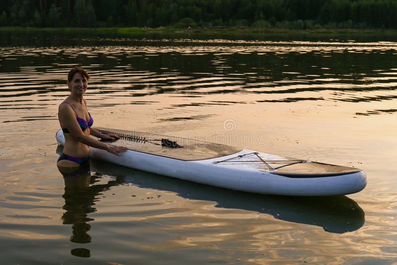 A Lone Woman Rides a Sup Board on a Lake Surrounded by Grass and Dense ...