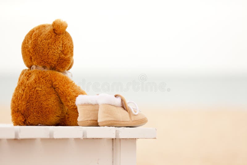 Loneliness teddy bear and baby s bootees stay on a sunbed