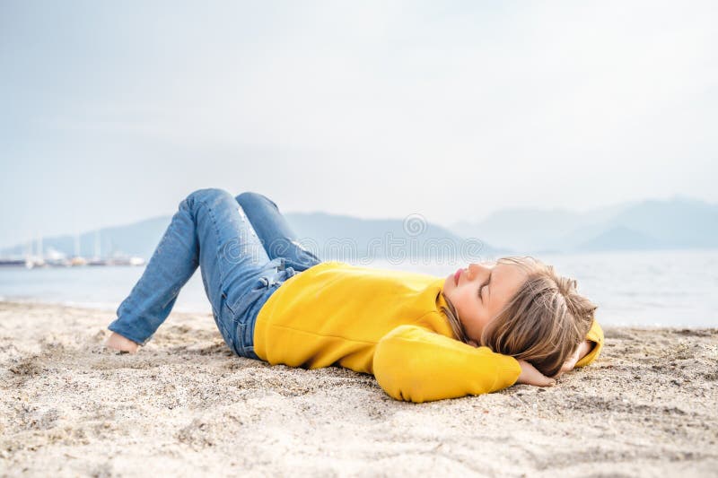 Lonely beautiful sad girl teenager lying sleeping on sand sea beach. Dreams,anxiety,worries about future,school friends