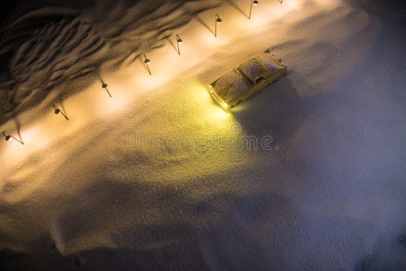 Lonely Car driving on a snow covered road with street lamps in snowy weather at night. Artwork decoration for greeting card. New Year and Christmas concept