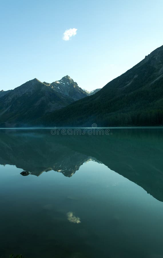 Lonely cloud above dark blue lake royalty free stock photos