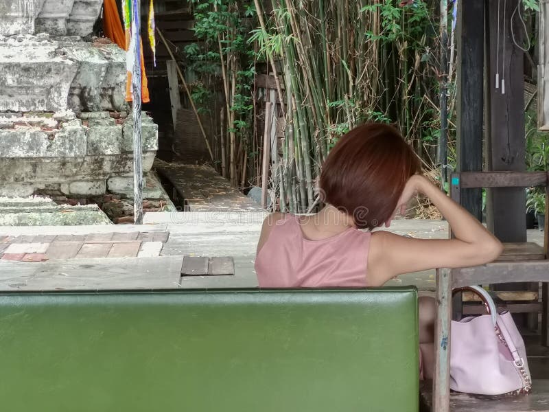 Lonely desperate woman with pink dress and pink handbag thinking alone sitting on a green bench royalty free stock images Lonely desperate woman with pink dress and pink handbag thinking alone sitting on a green bench royalty free stock images