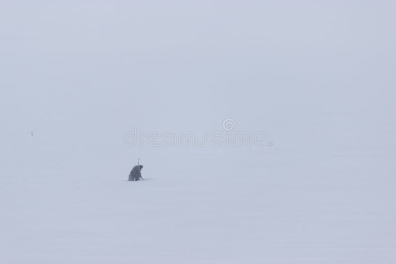 Lonely fisherman sitting on the frozen river stock photos