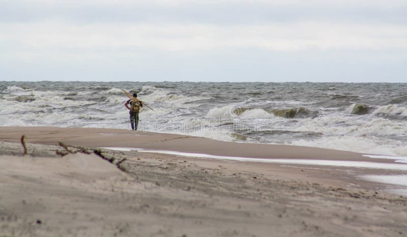 Lonely man on the beach. Amber gathering, stormy weather.