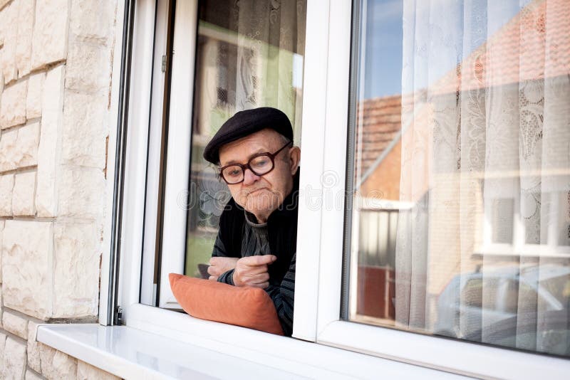 Senior man looking out of window in a loft flat stock photo