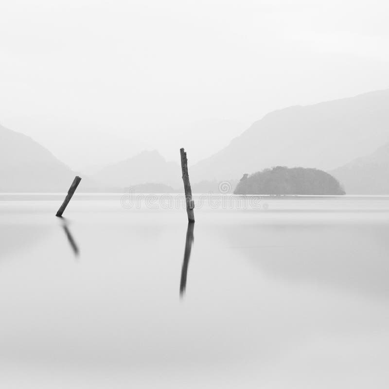 Lonely posts in still water lake Derwent Water Lake District UK peace quiet mindfulness relaxation