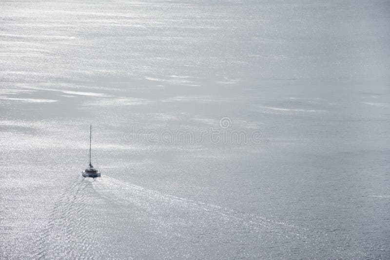 Lonely sailing boat in the vastness of aegean sea, Santorini.
