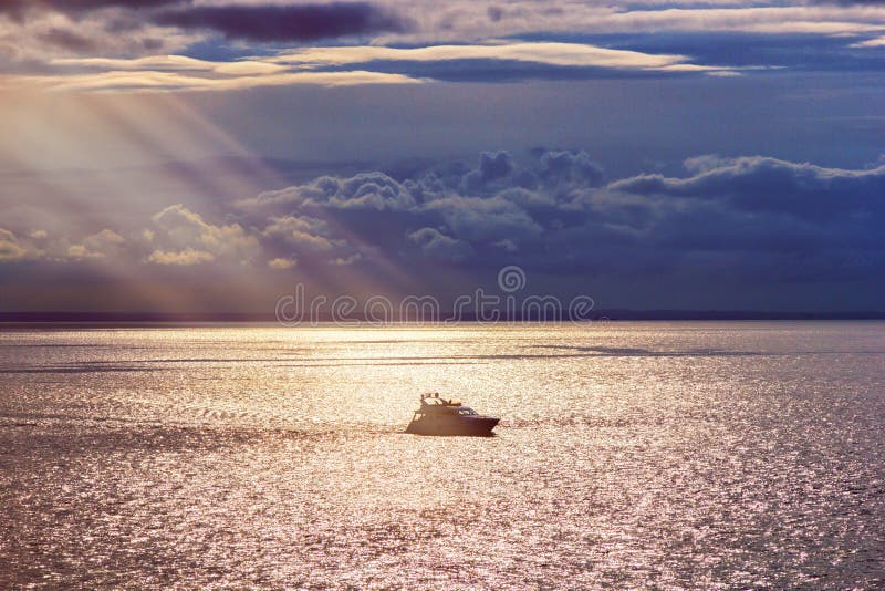 Lonely ship at sunset lit by the rays of the sun royalty free stock photography