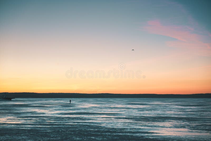 Lonely silhouette of a traveler on the lake covered with ice royalty free stock photo