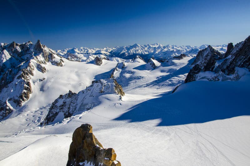 Lonely ski slope in the top of french Alps. All around the summits of Alps covered with snow. Photographed from the top of Aiguille du Midi. Winter holiday in Chamonix-Mont-Blanc during sunny day. Best place for winter holiday, skiing and snowboarding. Lonely ski slope in the top of french Alps. All around the summits of Alps covered with snow. Photographed from the top of Aiguille du Midi. Winter holiday in Chamonix-Mont-Blanc during sunny day. Best place for winter holiday, skiing and snowboarding.