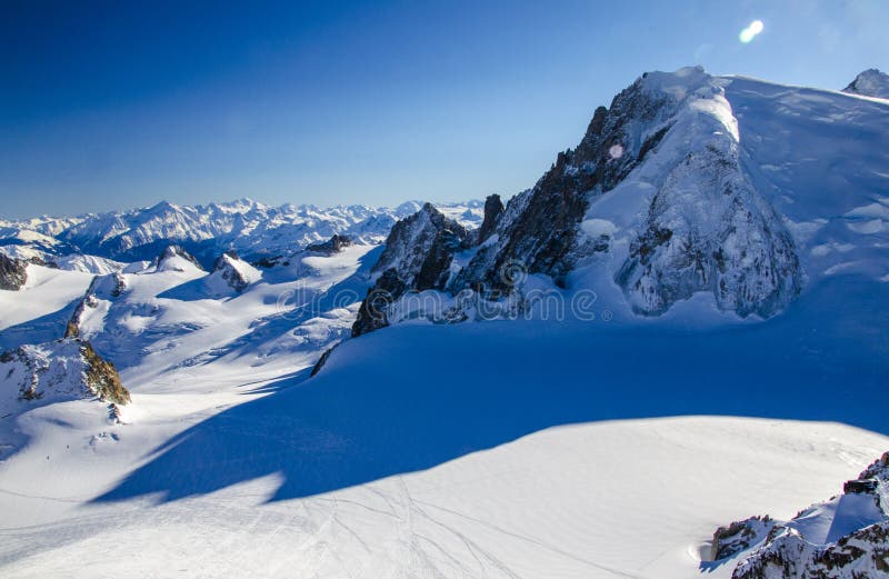 Lonely ski slope in the top of french Alps. All around the summits of Alps covered with snow. Photographed from the top of Aiguille du Midi. Winter holiday in Chamonix-Mont-Blanc during sunny day. Best place for winter holiday, skiing and snowboarding. Lonely ski slope in the top of french Alps. All around the summits of Alps covered with snow. Photographed from the top of Aiguille du Midi. Winter holiday in Chamonix-Mont-Blanc during sunny day. Best place for winter holiday, skiing and snowboarding.