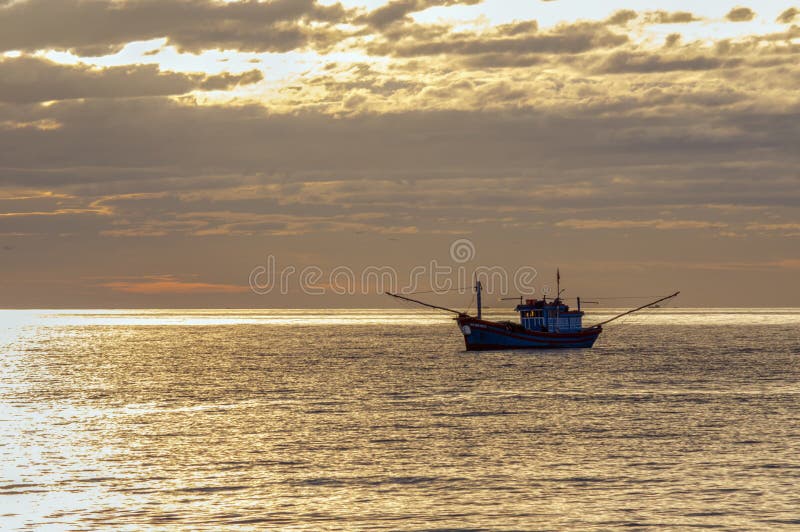 Lonely small fishing boat on the ocean stock photography