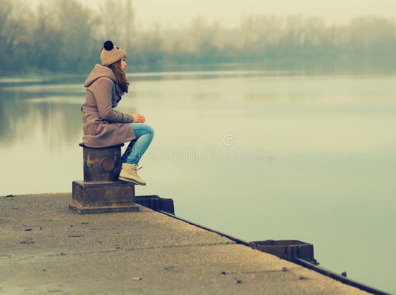 Lonely teenage girl sitting on the dock