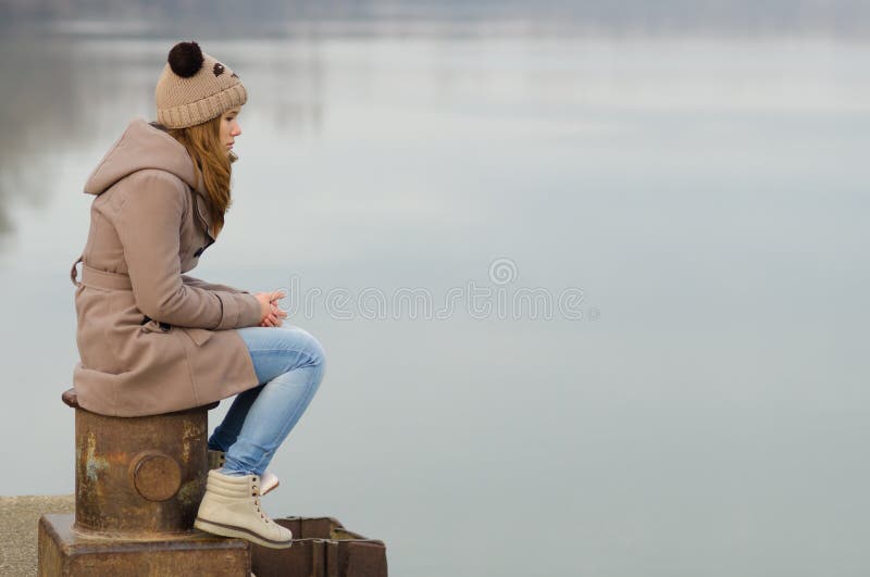 Lonely teenage girl sitting on the dock stock photo Lonely teenage girl sitting on the dock stock photo