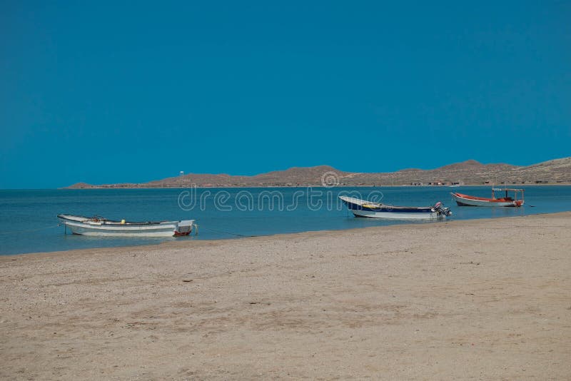 Lonely traditional Colombian fishing boats on sea water with clear water and blue sky - at Cabo de la vela, La guajira, Colombia