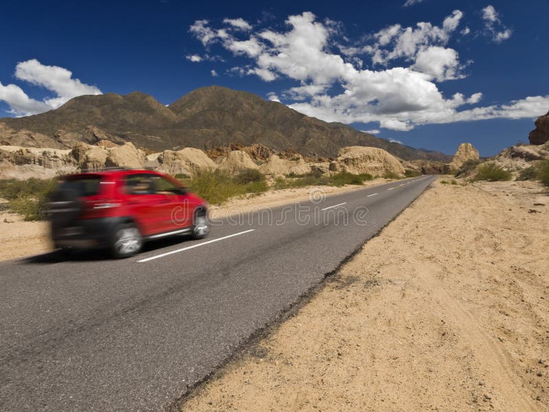 A fast car on the road in a arid and rocky landscape. A fast car on the road in a arid and rocky landscape.
