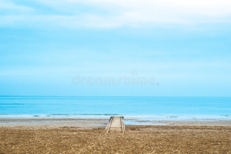 Lonely wood pier during cloudy day with calm sea and blue quiet sky stock photo Lonely wood pier during cloudy day with calm sea and blue quiet sky stock photo
