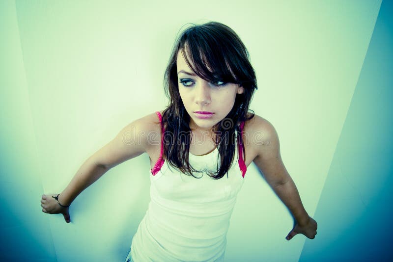 A young woman backs herself to the wall, seemingly scared or lonely. A young woman backs herself to the wall, seemingly scared or lonely.