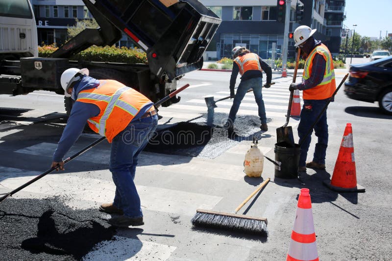 Long Beach, California / USA - March 15, 2021: Workers with Asphalting paver machine during Road street repair work. Street