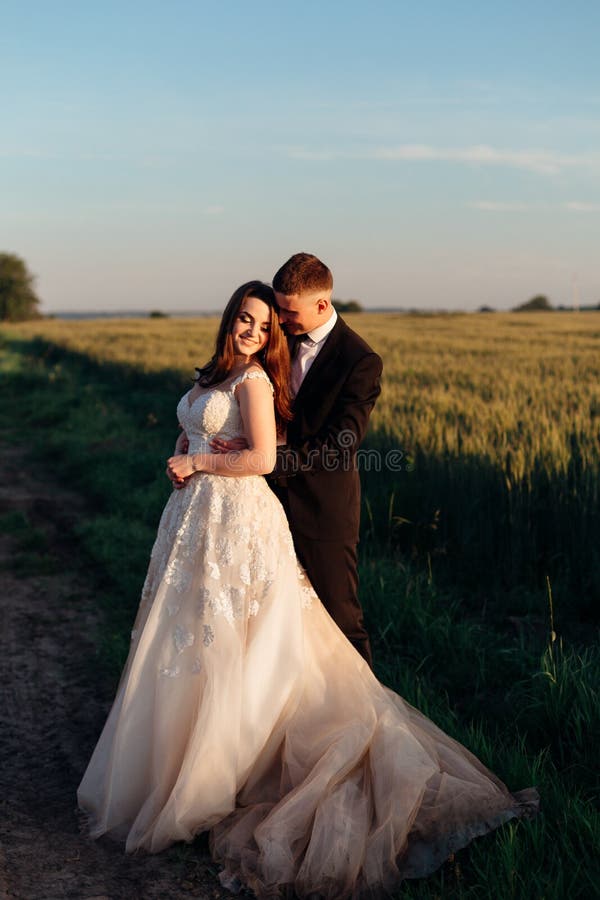 Long beige dress spreads on the ground around huggung couple