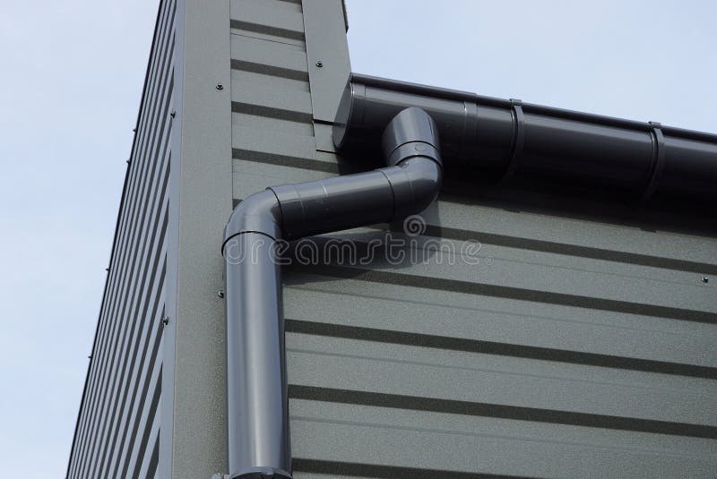 Long Black Plastic Drain Pipe on the Iron Wall of the Building Stock