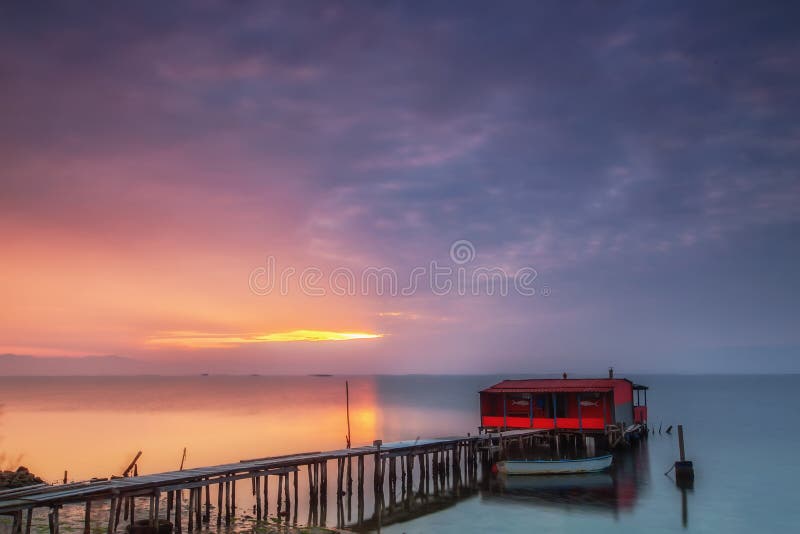 Long exposure of magic sunrise over the ocean with a hut in the