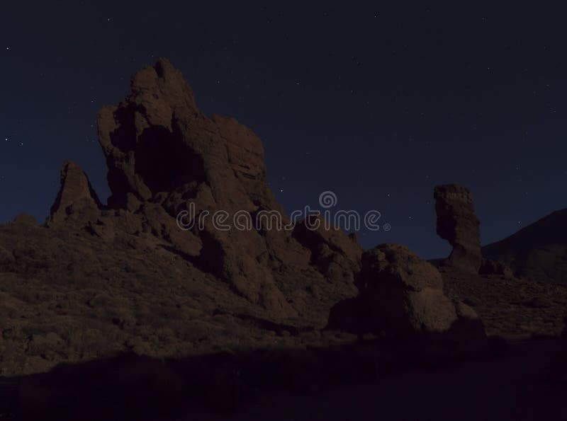 Long exposure night shot of Roques de Garcia with Roque Cinchado volcanic rock formation at El Teide national park, night winter sky with stars on dark blue. Tenerife Canary islands, Spain.