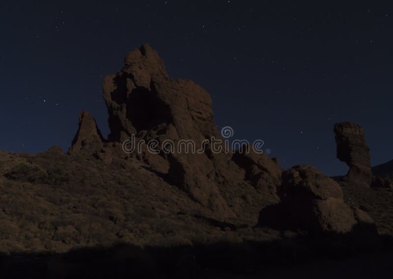 Long exposure night shot of Roques de Garcia with Roque Cinchado volcanic rock formation at El Teide national park, night winter sky with stars on dark blue. Tenerife Canary islands, Spain.