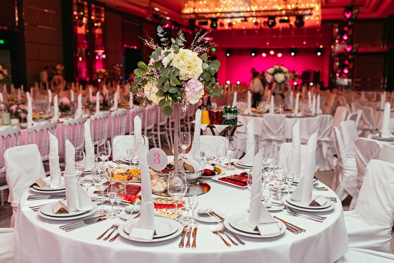 Long festive table served dishes and decorated with branches of greenery. Wedding banquet.