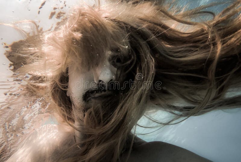 Artistic pic out of focus underwater with long hair man swimming with bubble in water, dark underwater atmosphere with nightmare human abyssal creature like mermaid with beard. Artistic pic out of focus underwater with long hair man swimming with bubble in water, dark underwater atmosphere with nightmare human abyssal creature like mermaid with beard