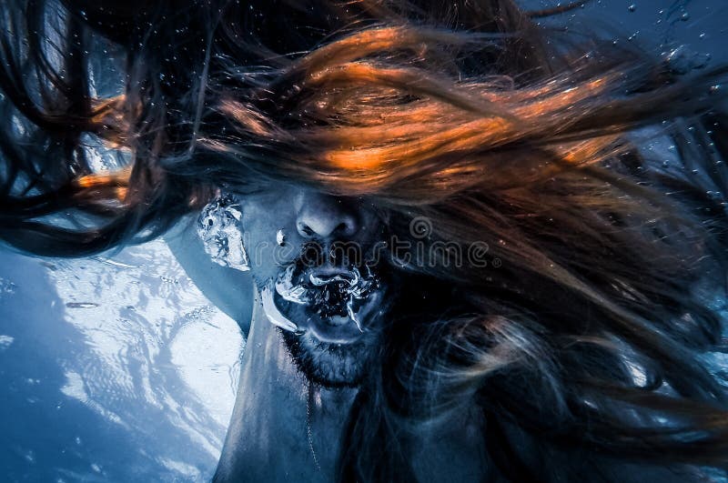 Artistic pic out of focus underwater with long hair man swimming with bubble in water, dark underwater atmosphere with nightmare human abyssal creature like mermaid with beard. Artistic pic out of focus underwater with long hair man swimming with bubble in water, dark underwater atmosphere with nightmare human abyssal creature like mermaid with beard