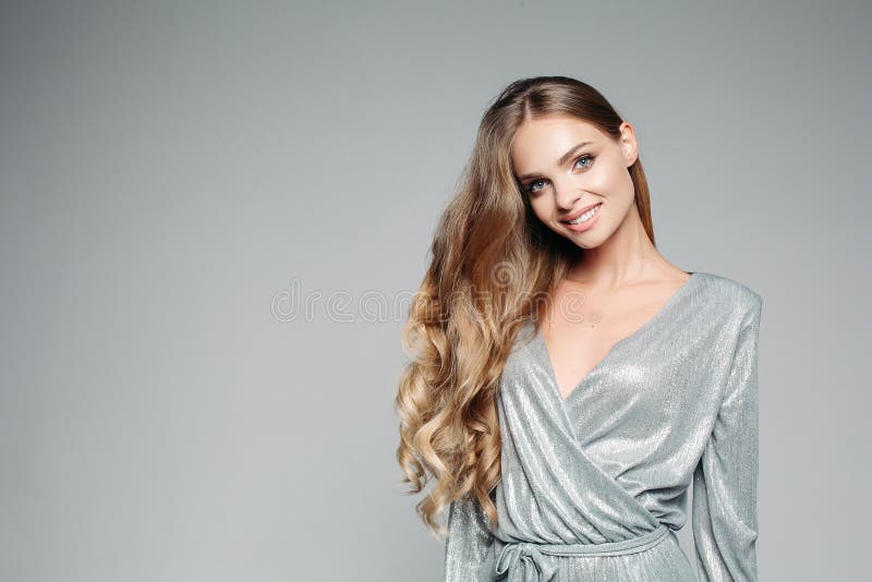 Long haired blondie woman in shiny silver outfit smiling at camera.